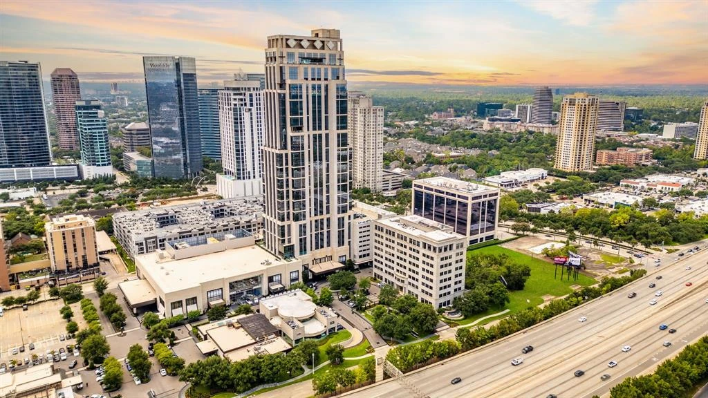 Aerial view of Houston high-rise buildings, neighboring streets, and a freeway at sunset.