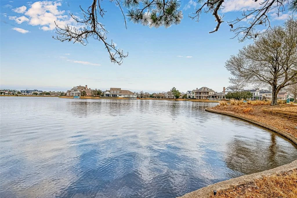 Neighborhood lake framed by trees, with homes along the opposite shoreline.